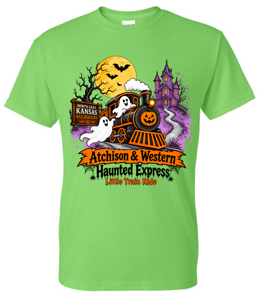 A bright lime green short-sleeve t-shirt with a colorful Halloween-themed graphic on the front. The graphic features a cartoon orange train with white ghosts, a jack-o'-lantern moon, a haunted house, and text reading 'Atchison & Western Haunted Express' and 'Little Train Ride'.